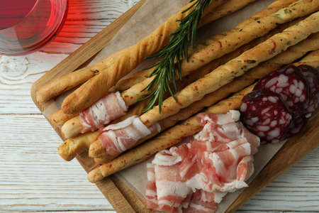 Grissini sticks with bacon and wine on white wooden backgroundの写真素材