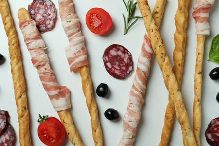 Grissini sticks with bacon and snacks on white backgroundの写真素材