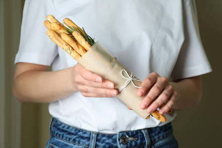 Woman hold tasty grissini sticks in paperの写真素材