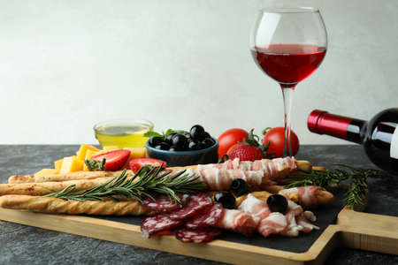 Board with grissini and snacks, and wine on black smokey tableの写真素材