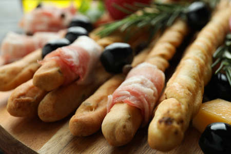 Tasty grissini sticks with bacon and snacks, close upの写真素材