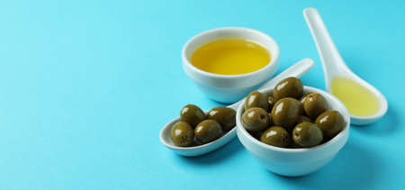 Spoons and bowls with olives and oil on blue backgroundの写真素材