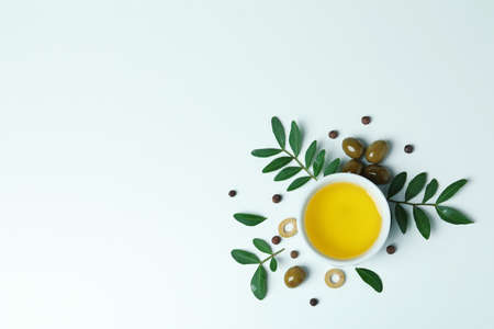 Bowl of oil, olives and twigs on white backgroundの写真素材