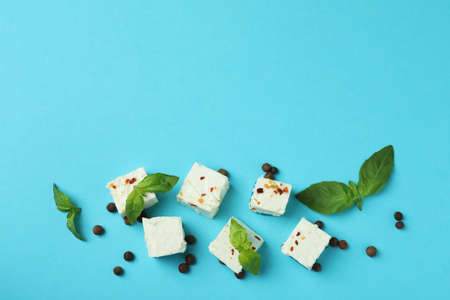 Feta cheese pieces and spices on blue background