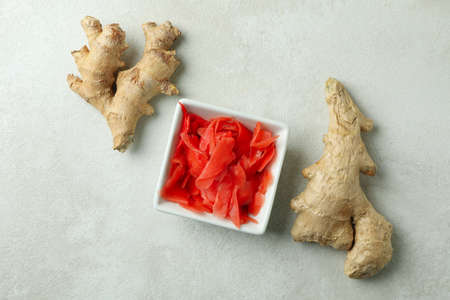Bowl with red pickled ginger and ginger on white textured background