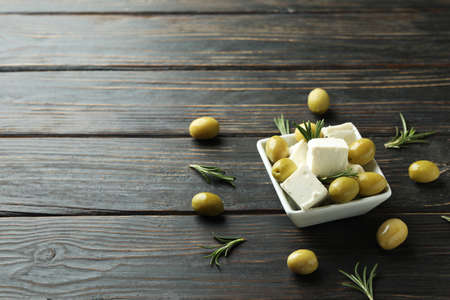 Bowl with feta cheese, olives and rosemary on wooden backgroundの写真素材