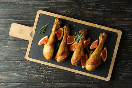 Board with roast chicken drumsticks on wooden backgroundの写真素材