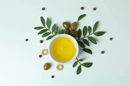 Bowl of oil, olives and twigs on white backgroundの写真素材