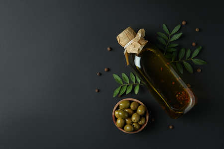 Bottle of olive oil, bowl of olives, twigs and pepper on black backgroundの写真素材