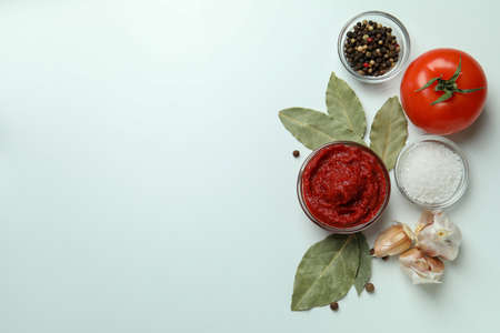 Bowl with tomato paste on white background with ingredientsの写真素材