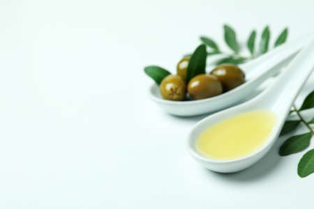Spoons with olives and oil, and twigs on white backgroundの写真素材