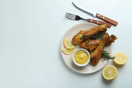 Concept of delicious eating with plate of roast chicken drumsticks on white backgroundの写真素材