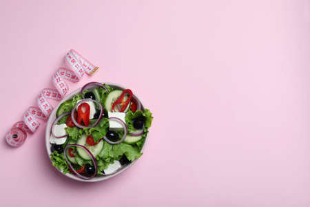 Bowl of greek salad and measuring tape on pink backgroundの写真素材