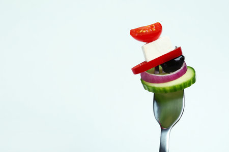Fork with greek salad ingredients on white backgroundの写真素材