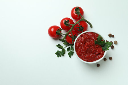 Bowl with tomato paste, tomatoes, pepper and parsley on white backgroundの写真素材