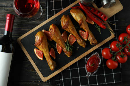 Concept of delicious eating with board of roast chicken drumsticks on wooden tableの写真素材