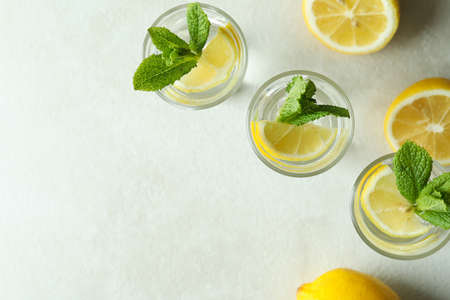 Shots with lemon slice and mint on white textured tableの写真素材