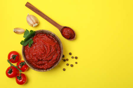 Bowl of tomato paste and ingredients on yellow backgroundの写真素材