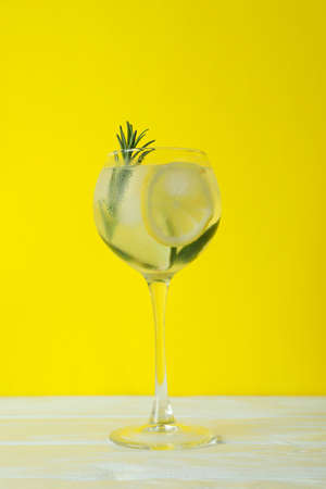 Glass of cocktail with lemon and rosemary on yellow backgroundの写真素材