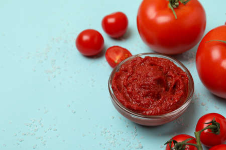 Bowl with tomato paste, tomatoes and salt on blue backgroundの写真素材