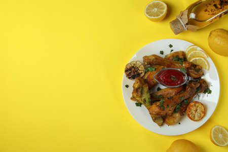 Concept of delicious eating with plate of roast chicken drumsticks on yellow backgroundの写真素材