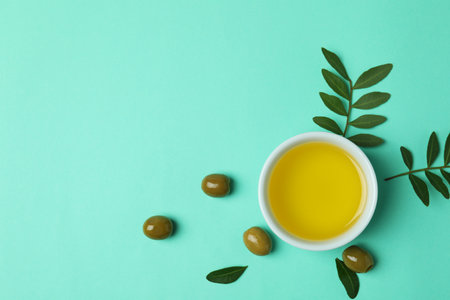 Bowl with olive oil, olives and twigs on mint backgroundの写真素材