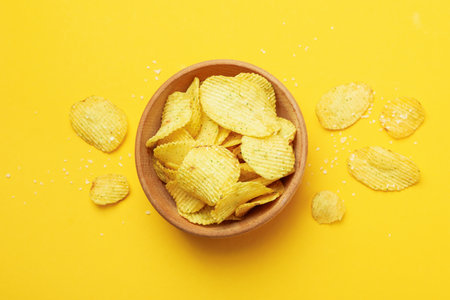 Bowl with potato chips on yellow background