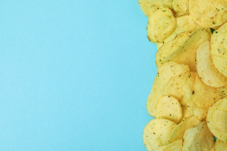 Potato chips on blue background, space for text
