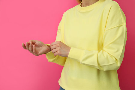 Young woman in yellow sweatshirt against pink backgroundの写真素材