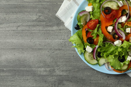 Plate of Greek salad and kitchen towel on gray textured backgroundの写真素材