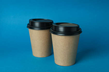 Blank paper cups on blue background, space for text