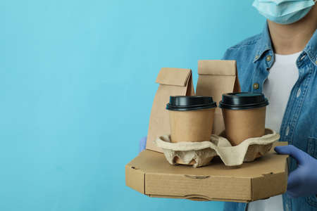 Woman hold delivery containers for takeaway food on blue background