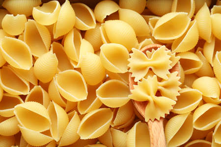 Uncooked pasta and spoon on whole background, space for text