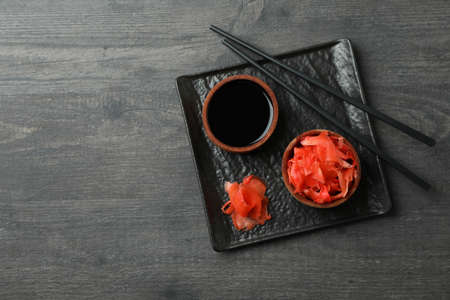 Plate with pickled ginger, soy sauce and chopsticks on dark wooden backgroundの写真素材