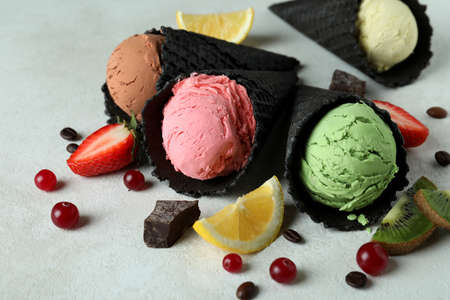 Black cones with ice cream and ingredients on white textured background