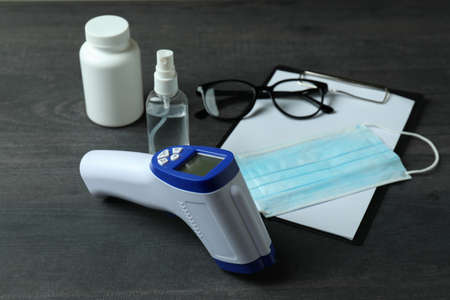 Medical tools and thermometer gun on dark wooden background