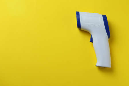 Thermometer gun on yellow background, space for textの写真素材