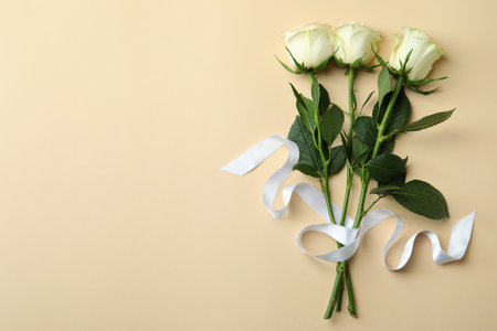 Beautiful roses with ribbon on beige backgroundの写真素材