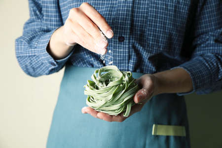 Woman hold uncooked green pasta and sprinkle flourの写真素材