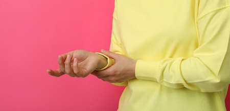 Young woman in yellow sweatshirt against pink background