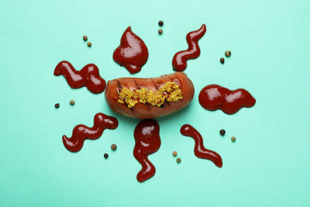 Grilled sausage with sauce and pepper on mint background