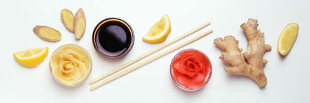 Pickled ginger, soy sauce, ginger, chopsticks and lemon on white background