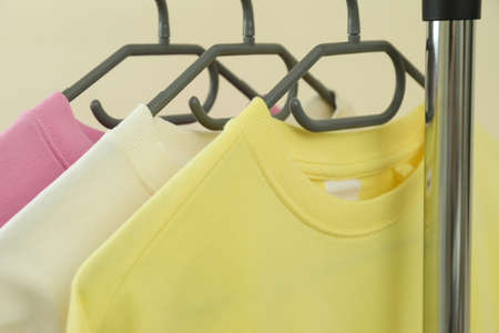 Wardrobe rack with sweatshirts against beige background