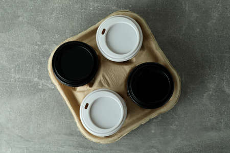 Cup holder with coffee cups on gray textured background