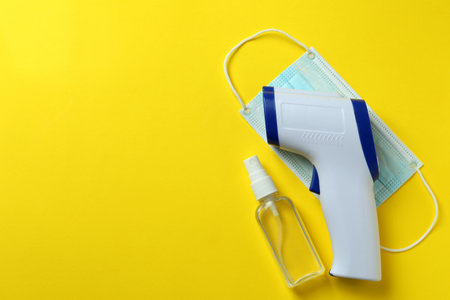 Medical tools and thermometer gun on yellow backgroundの写真素材