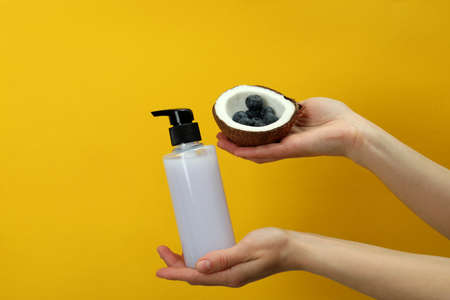 Female hands hold shower gel, coconut and blueberry on yellow backgroundの写真素材