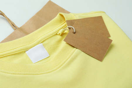 Sweatshirt with tags and bag on white background