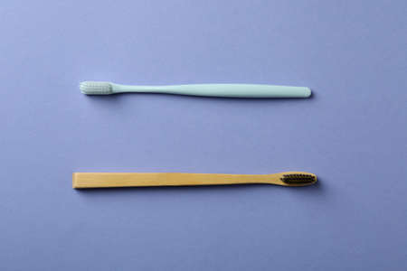 Eco friendly and plastic toothbrushes on violet background
