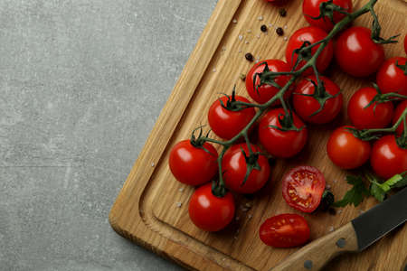 Cutting board with cherry tomato and knife on gray textured backgroundの写真素材