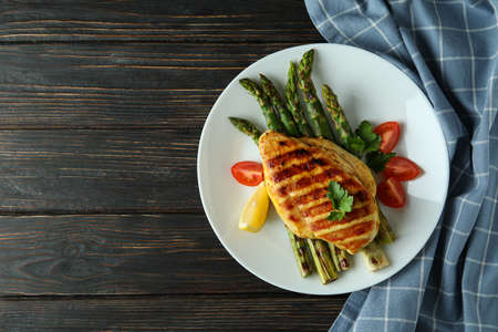 Plate with grilled chicken and ingredient on wooden backgroundの写真素材